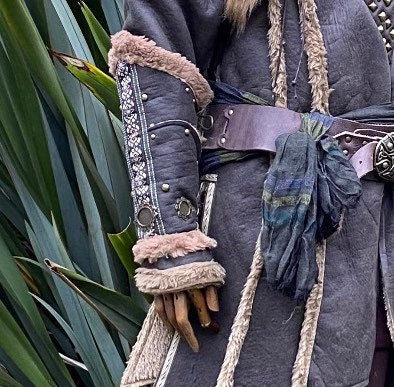 LARP vambraces with ornate pattern and fur, worn over medieval-style tunic.