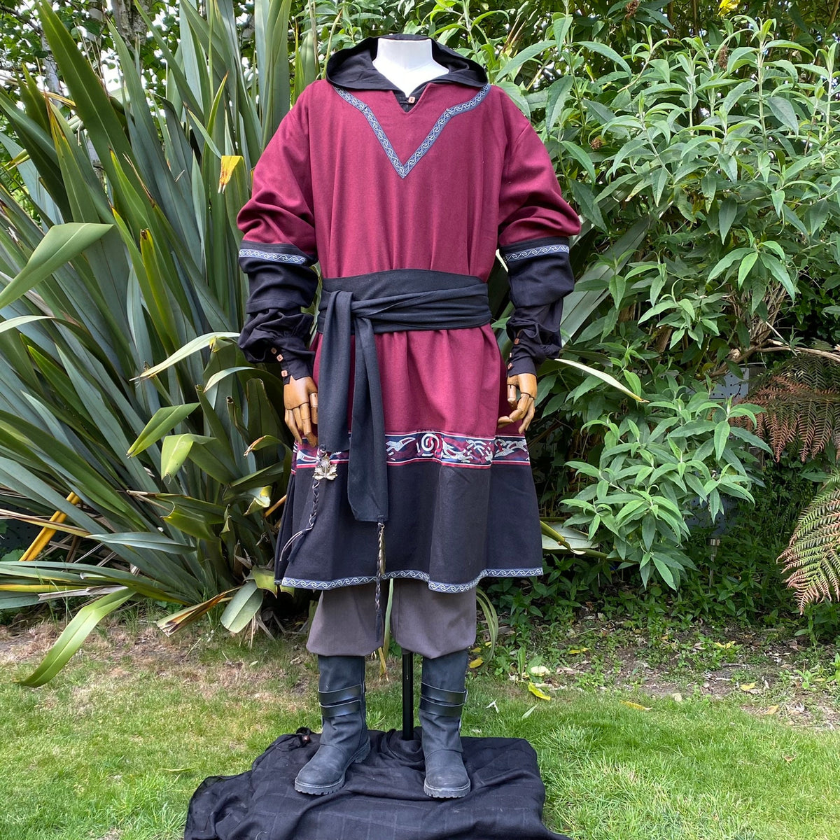 Medieval LARP attire: red tunic with detailed trim, black sash.