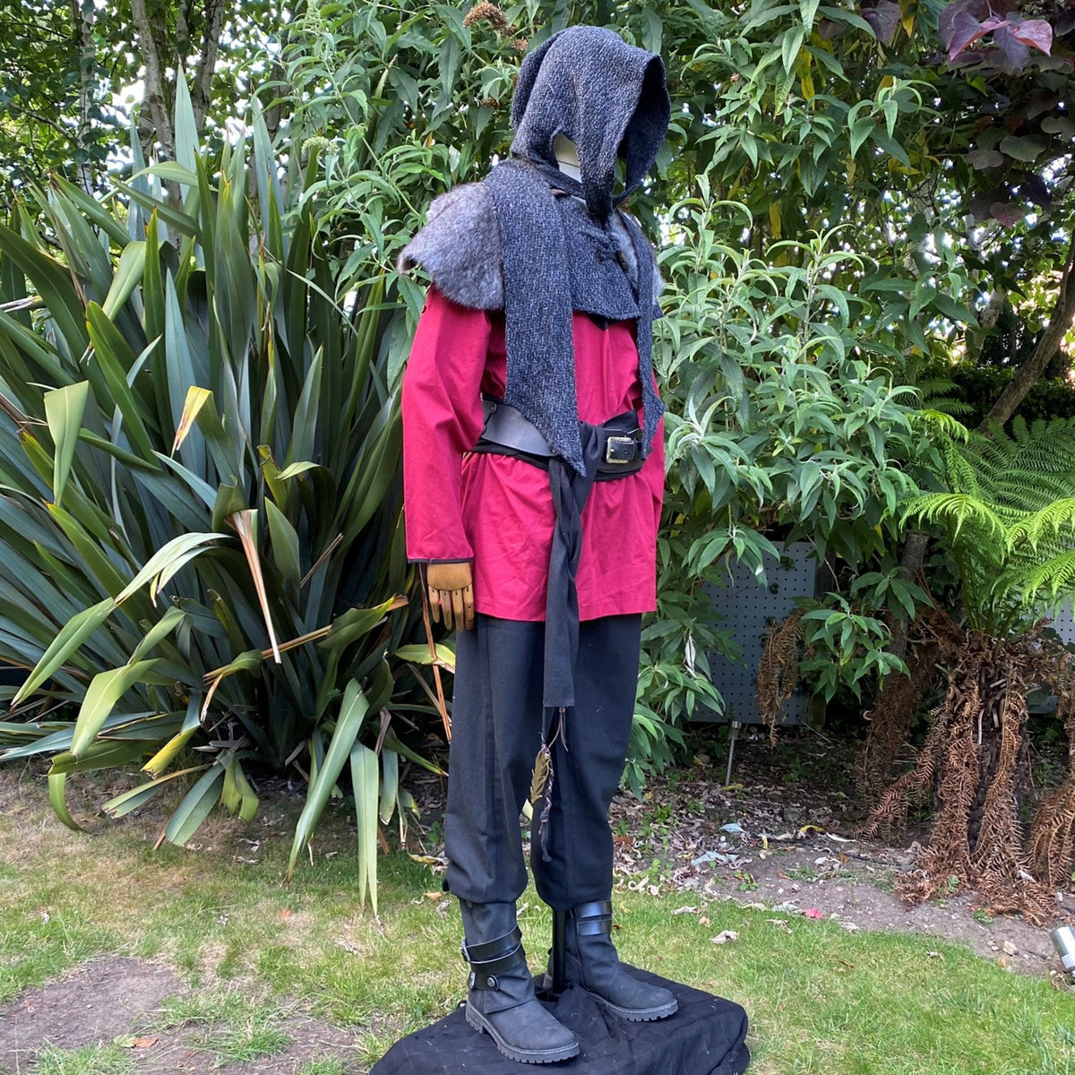 Medieval LARP outfit on mannequin in lush garden setting, side view.