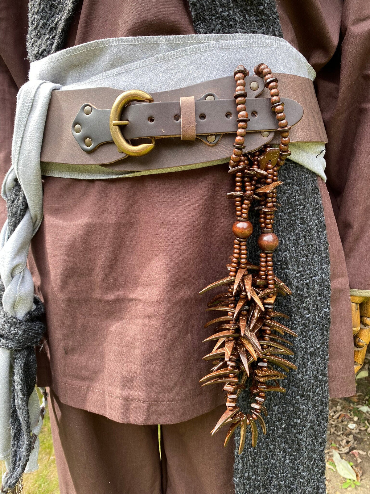 Brown tooth necklace with beads, hanging from medieval LARP belt.