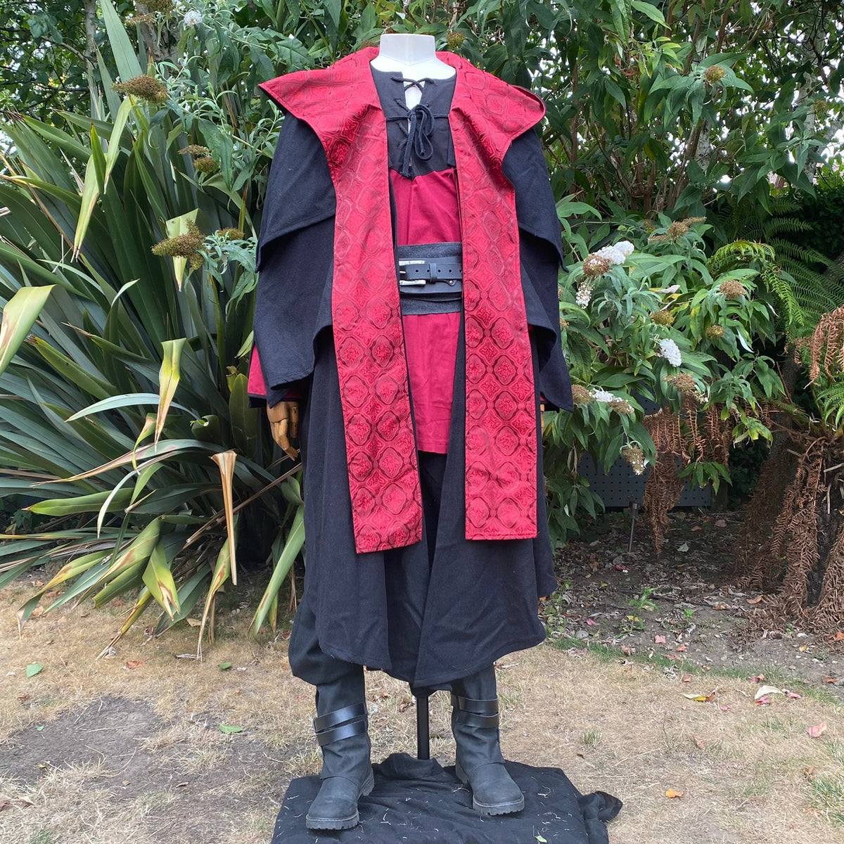 Blood Mage LARP set with red cloak, black trousers, and belt in natural setting.