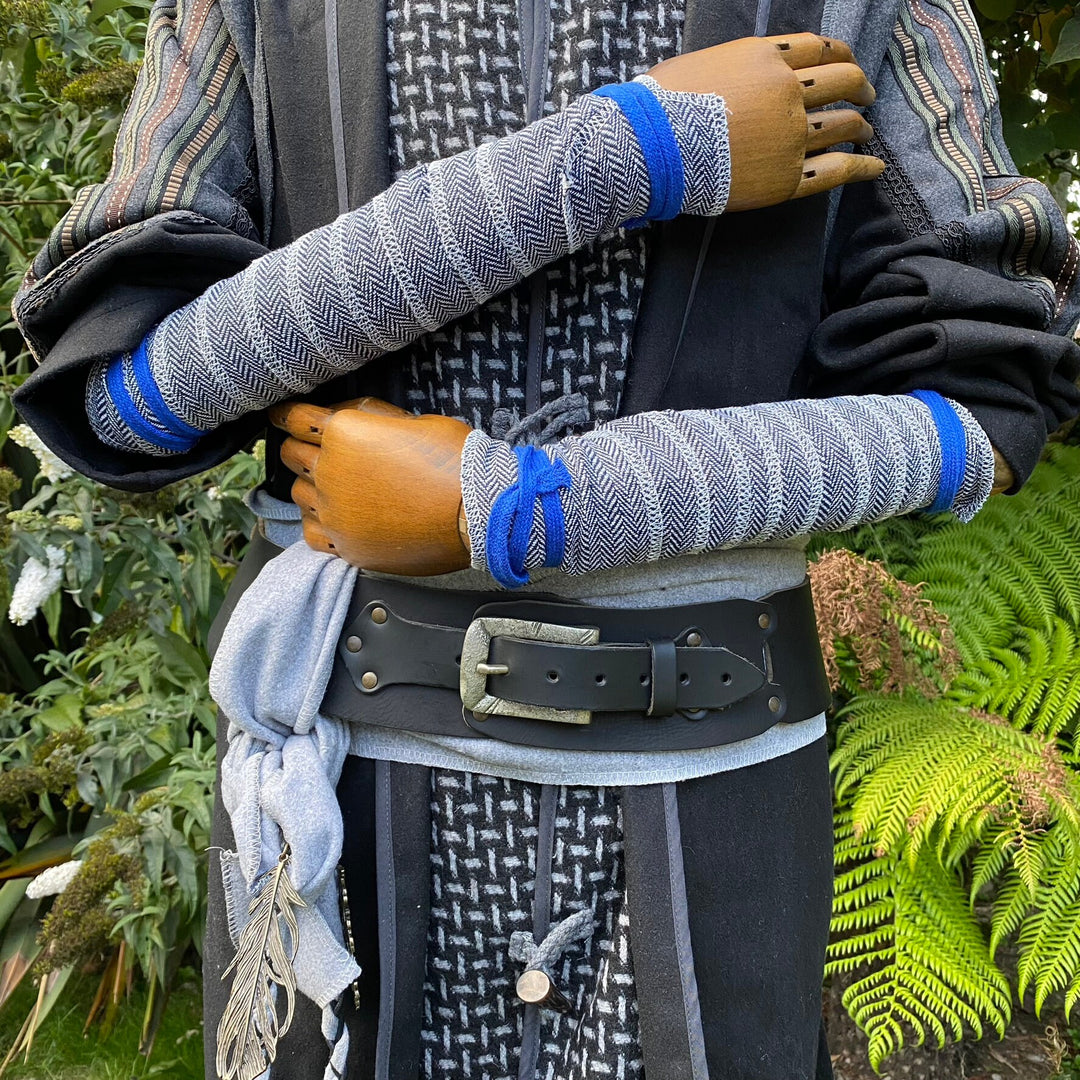Wooden mannequin in LARP attire, wrapped arms in blue-white herringbone wool.