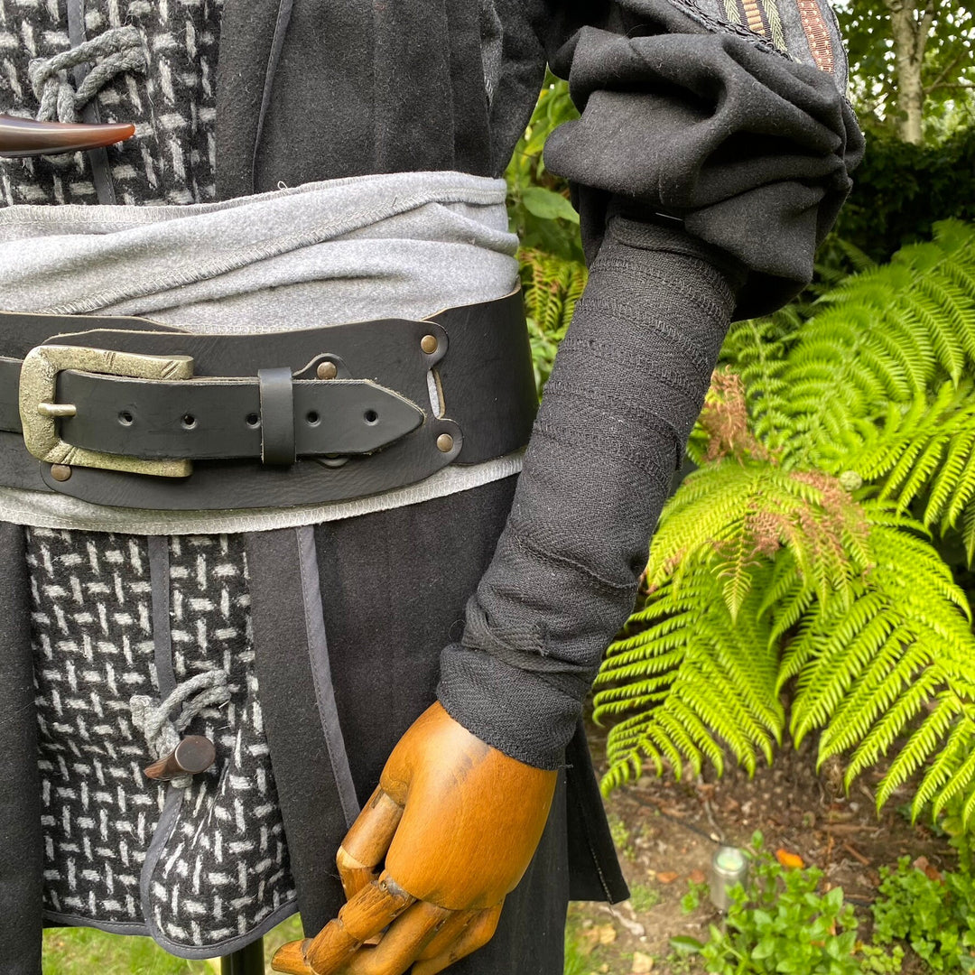 LARP medieval attire with black herringbone arm wrap close-up near ferns.