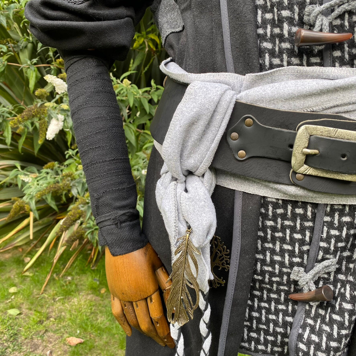 Medieval LARP costume detail with black arm wraps under foliage.