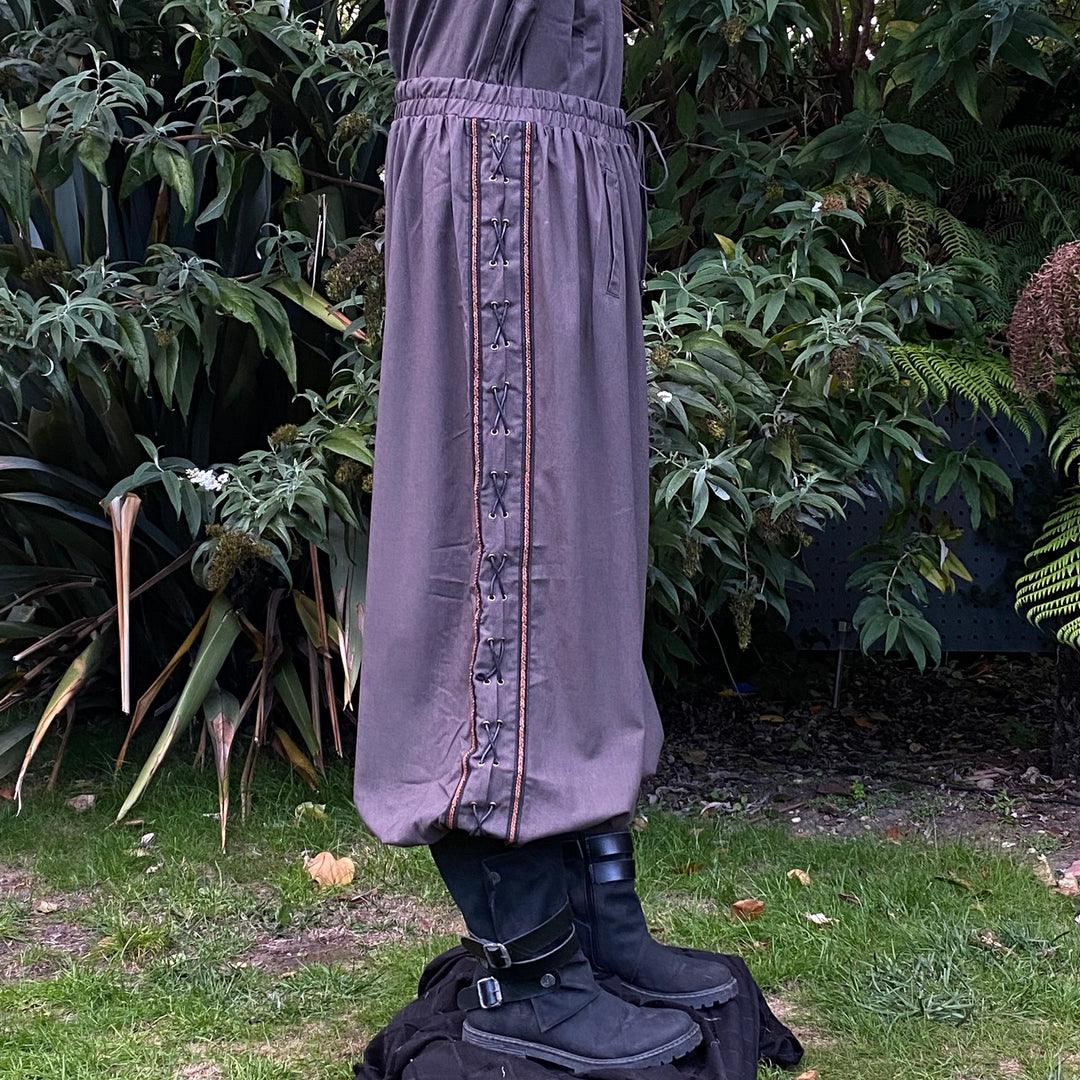 Side view of grey LARP pants with intricate side lace by greenery.