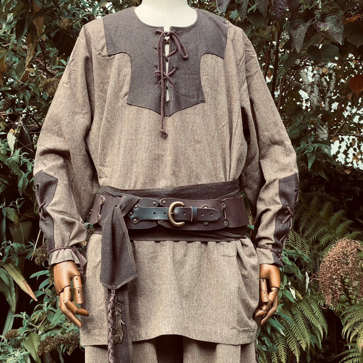 Mannequin in two-tone Viking shirt, brown belt, LARP forest setting.