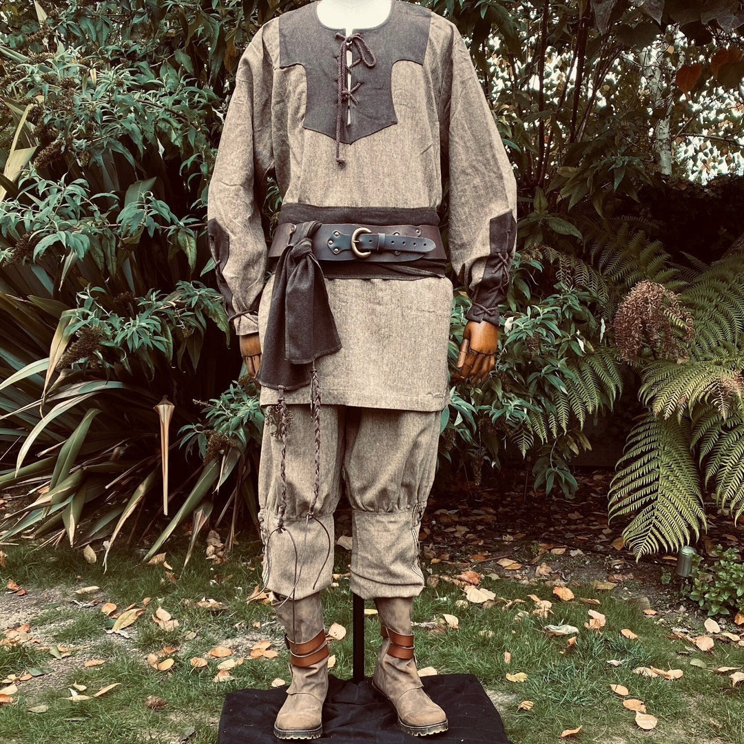 Two-tone Viking shirt front view with leather belt in medieval setting.