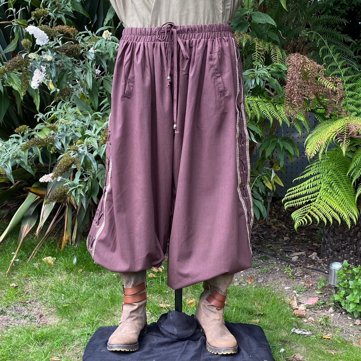 Brown medieval pants with side lace detail, garden backdrop, LARP attire.