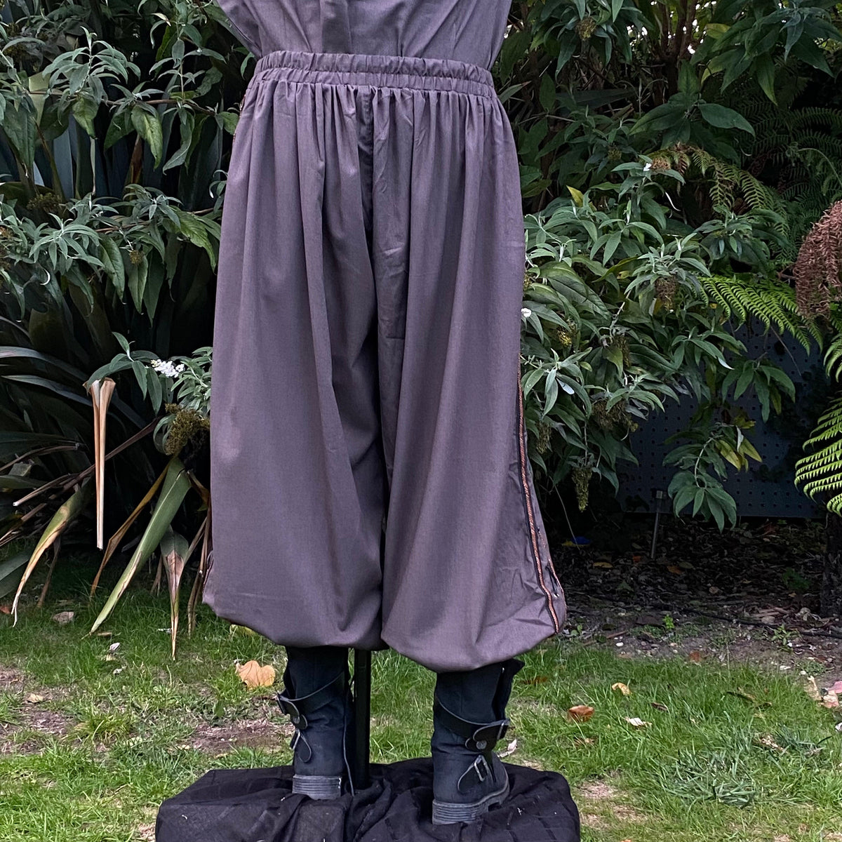 Rear view of grey LARP pants with side braiding.