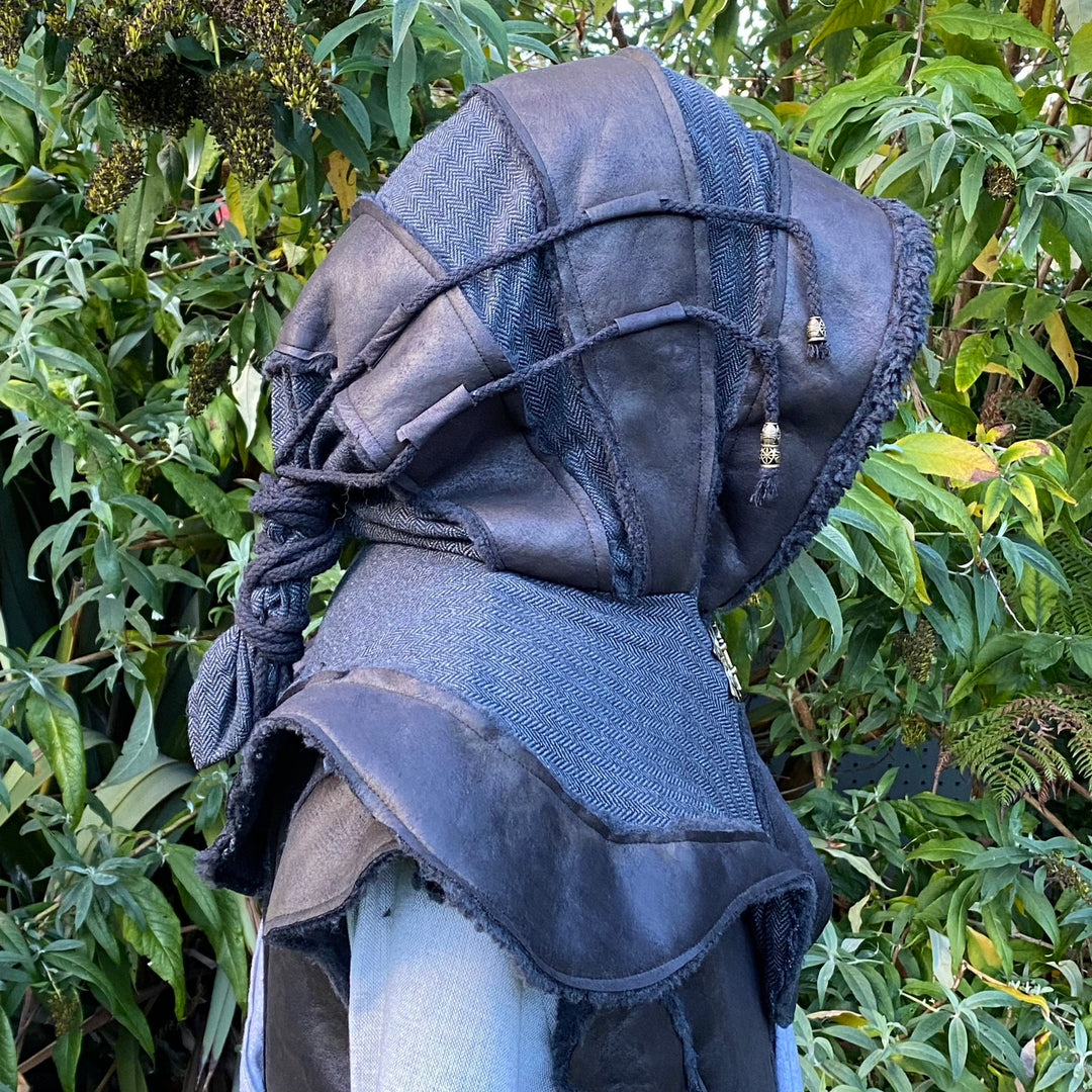 Side view of black faux leather LARP hood with braided detail and foliage backdrop.