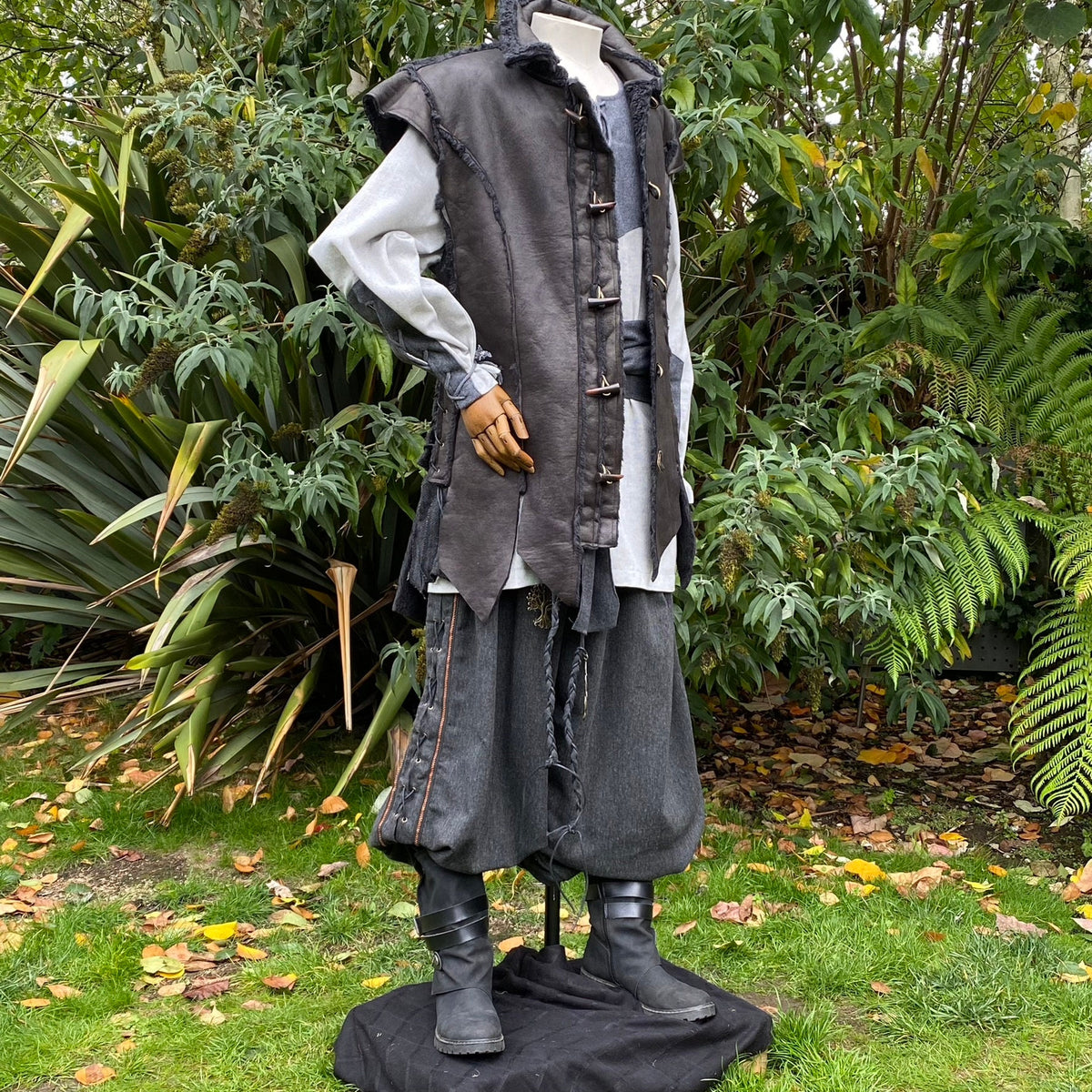 Three-quarter view of black medieval waistcoat showing horn toggle fastenings and layered textures.