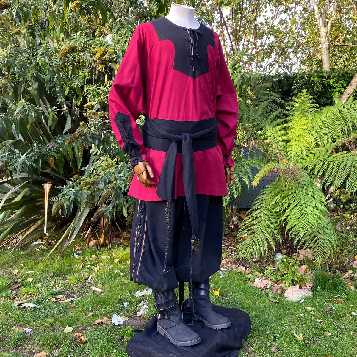 Mannequin in garden wearing red-black LARP Viking shirt with waist sash.