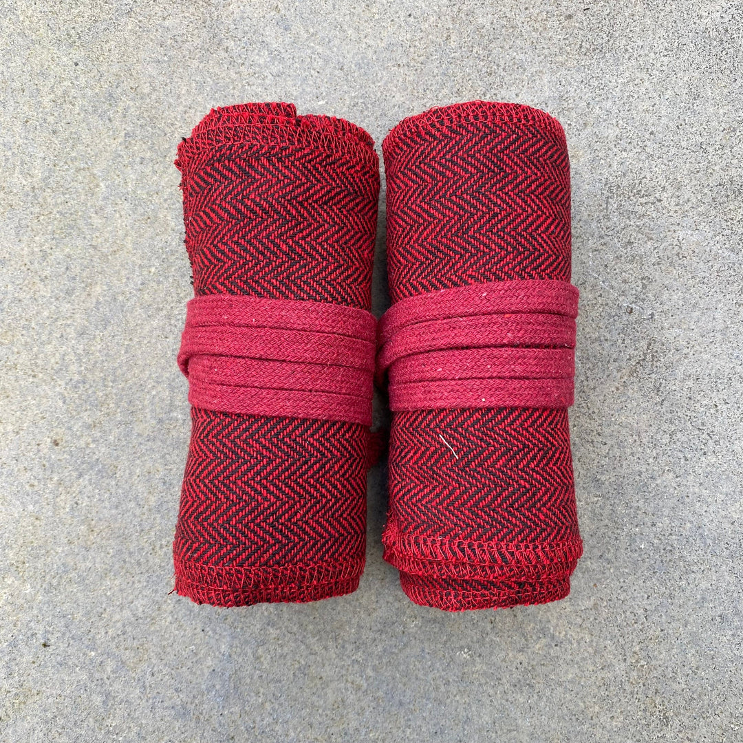 Rolled red herringbone wool leg wraps for LARP on concrete surface.