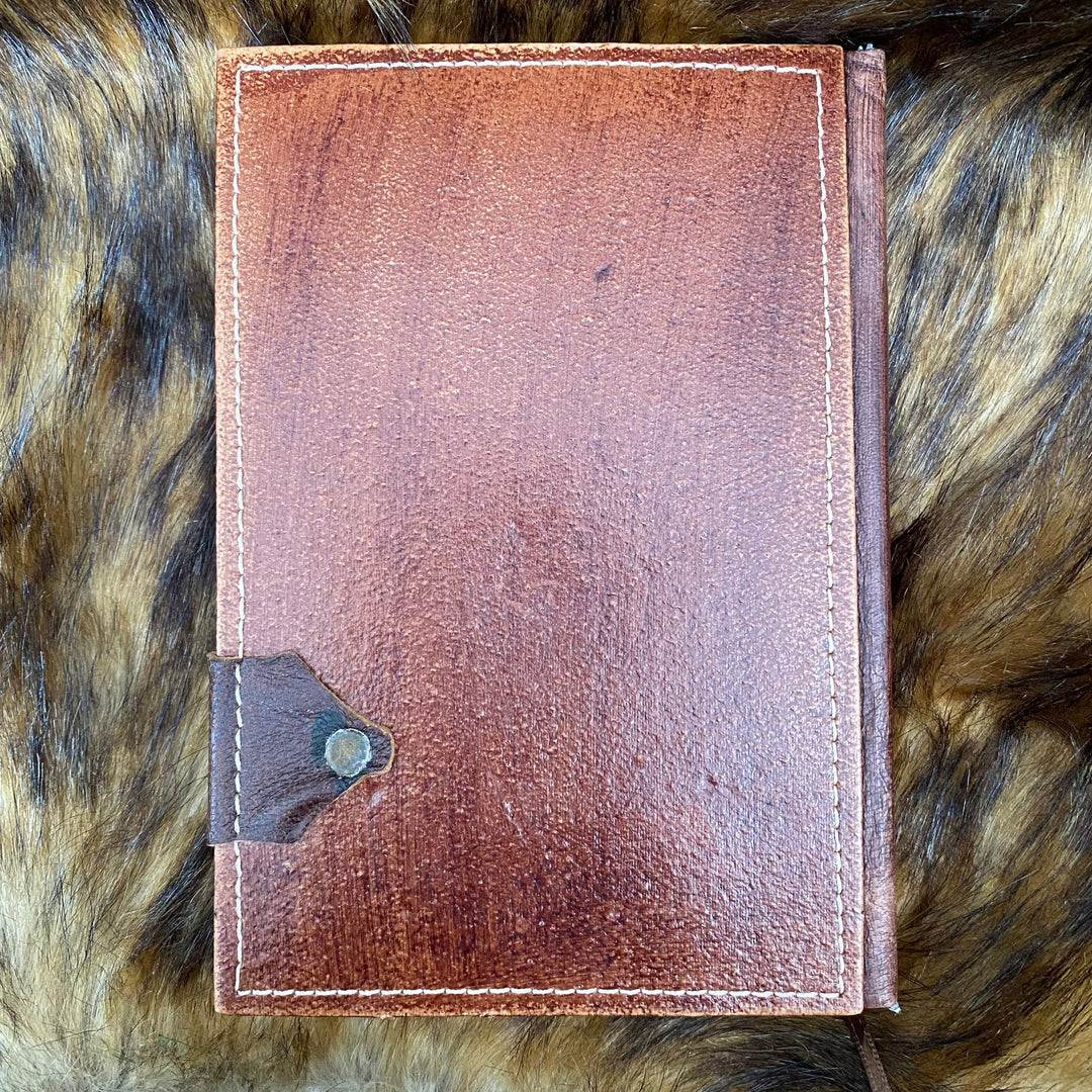 Brown leather LARP journal on fur, showcasing metal clasp and stitching.