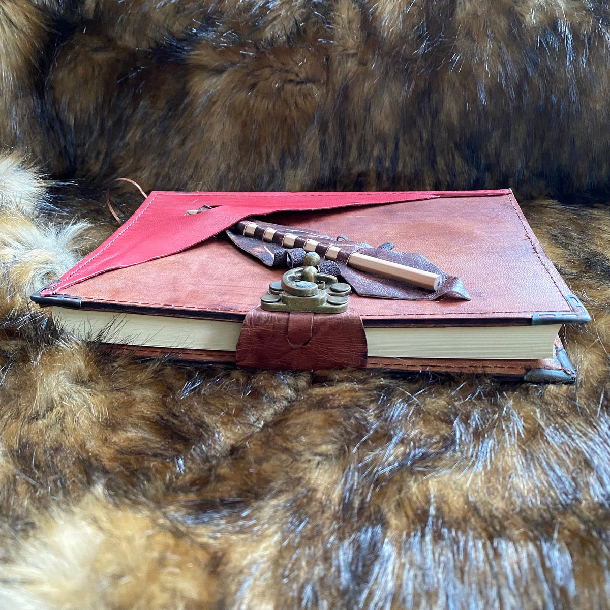 Medieval-style brown journal with pen pocket atop fur background.