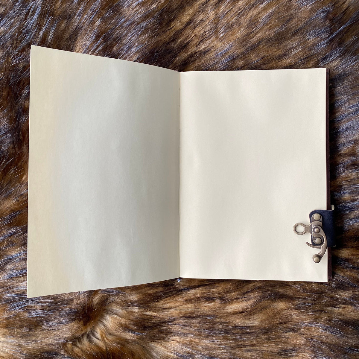 Open leather journal on fur, showcasing intricate metal clasp for LARP or medieval use.