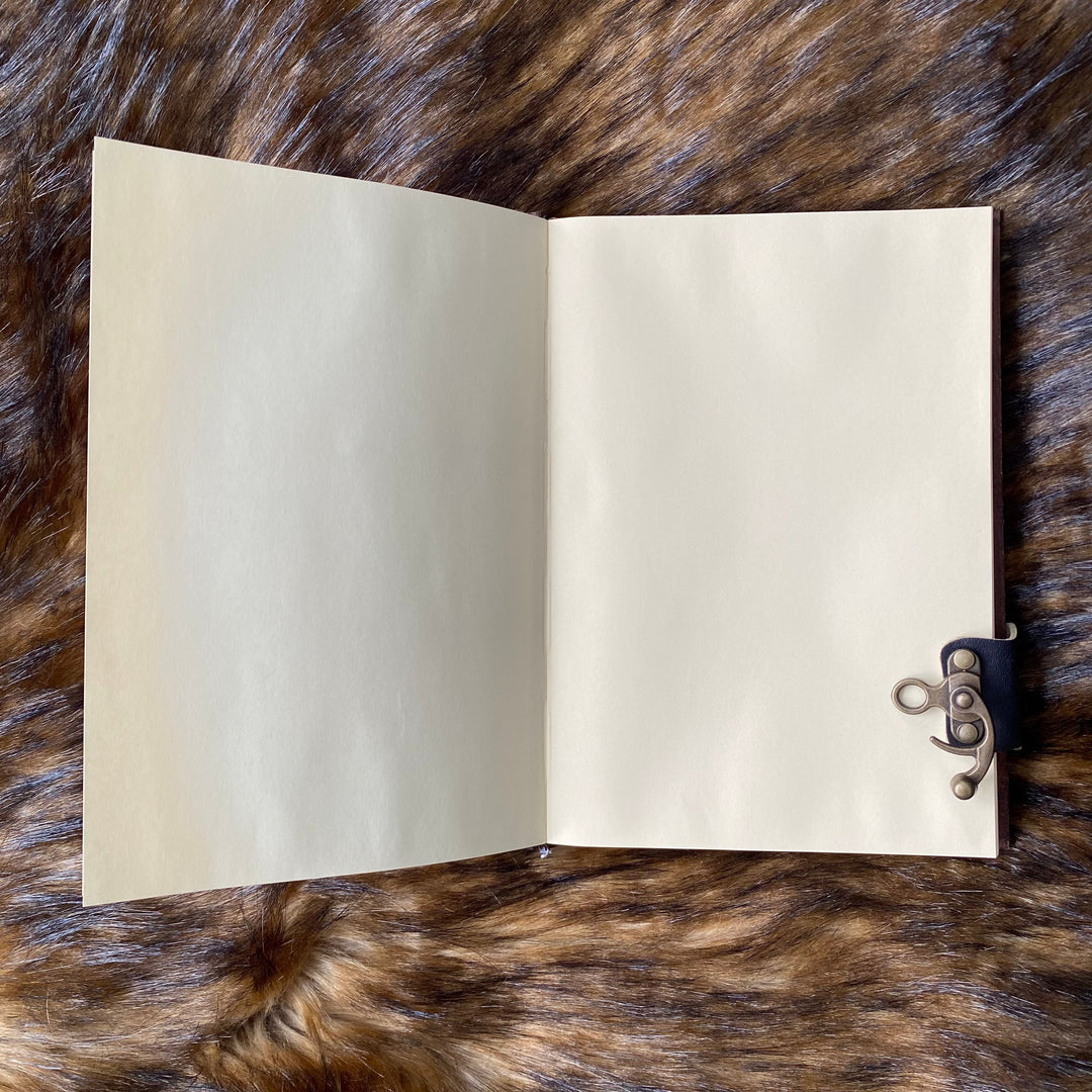 Open leather journal on fur, showcasing intricate metal clasp for LARP or medieval use.