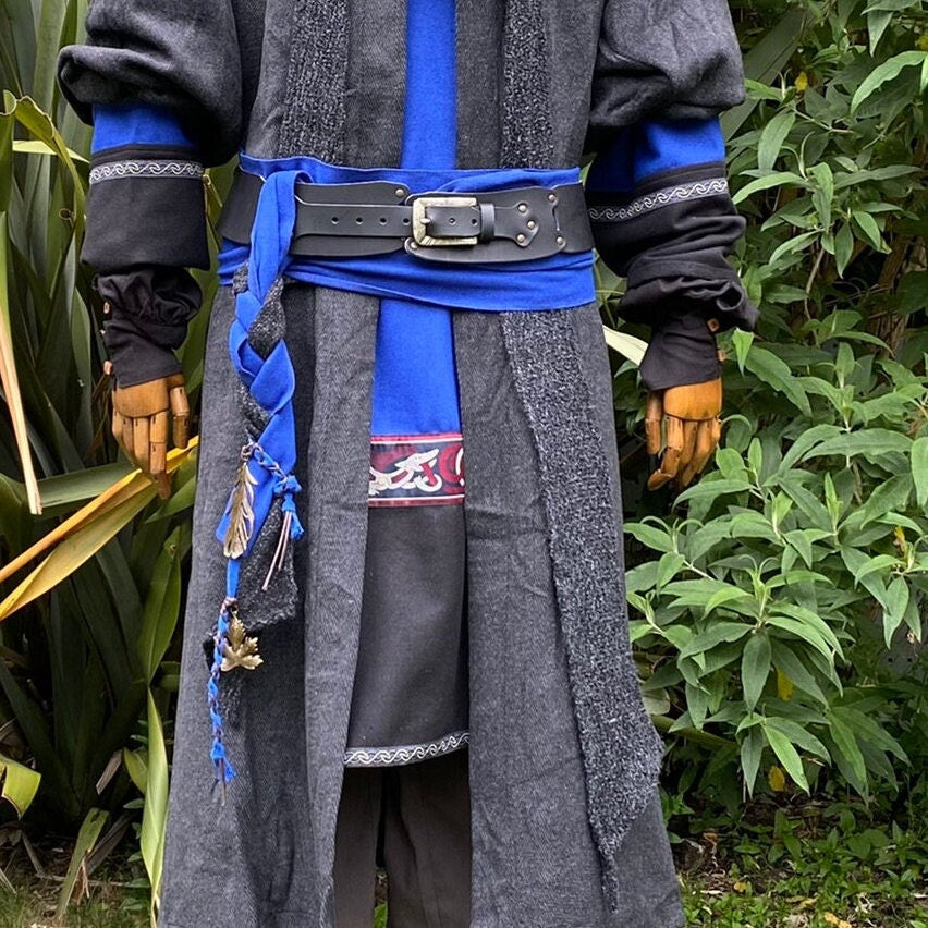 Medieval LARP costume with blue sash, black belt, and feather accents.