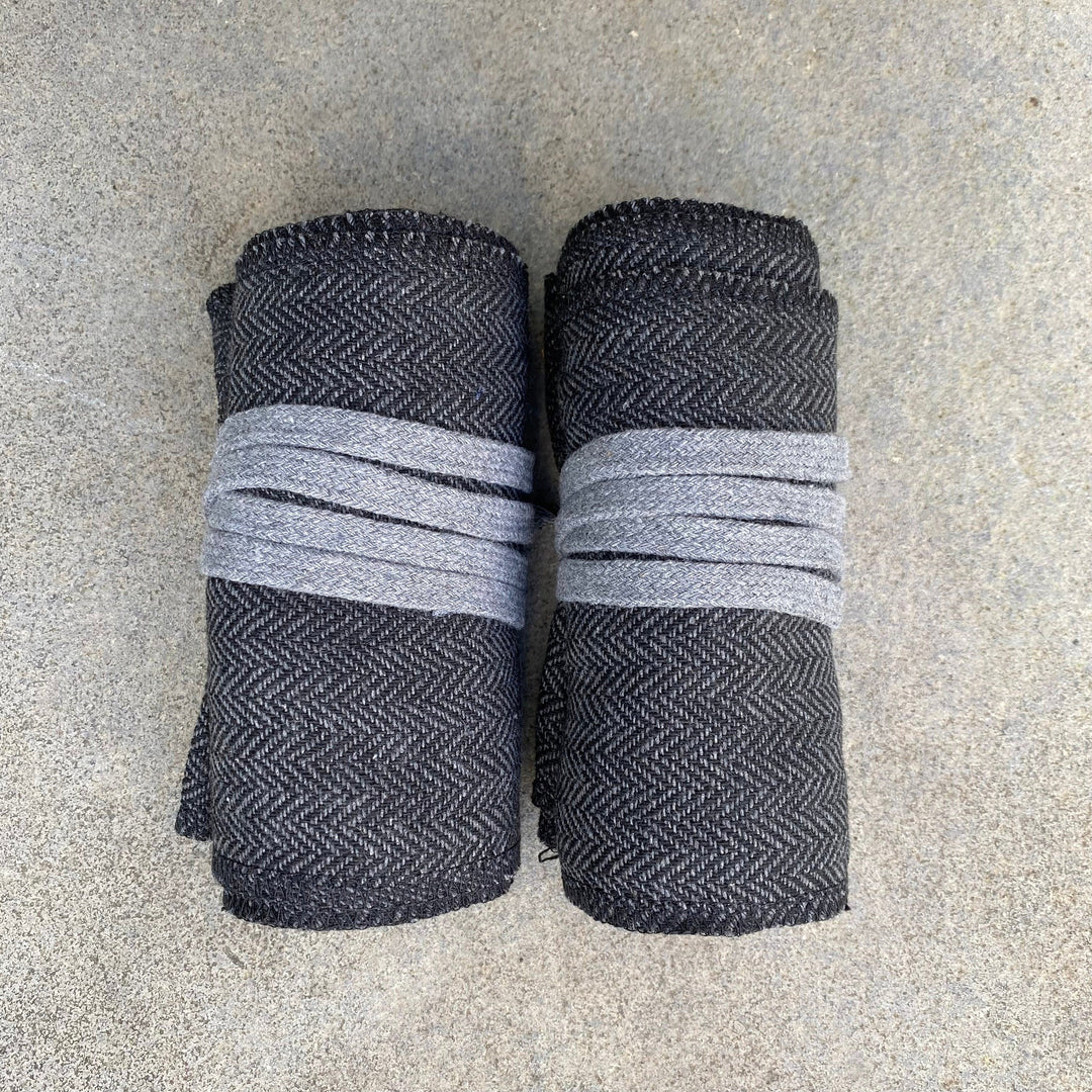Dark grey medieval leg wraps, top view, rolled with light grey ties.