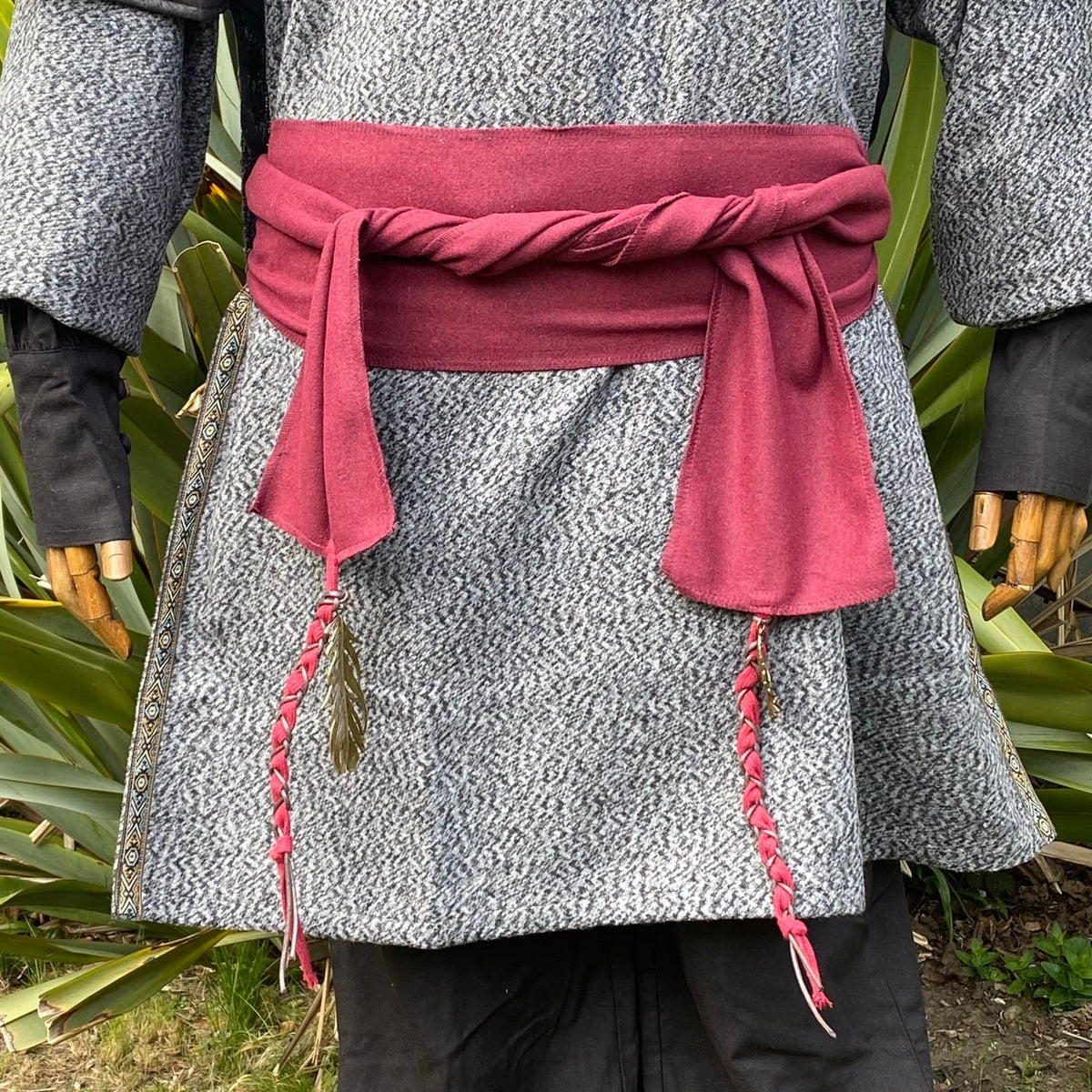 Medieval LARP red wool sash with braided detail and feather accents.