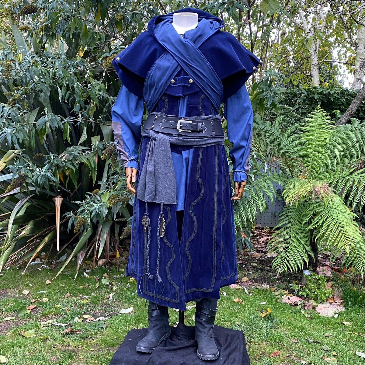 Mannequin in lush garden wearing LARP blue medieval outfit, black belt, wool sash.