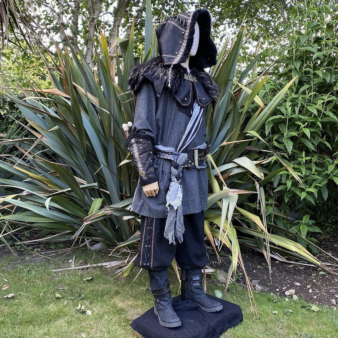 LARP rogue outfit side view, detailed hood, vambraces with nature backdrop.
