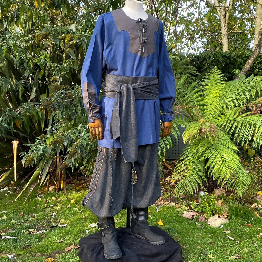 Mannequin in blue-grey LARP outfit outdoors, stylized medieval shirt and sash.
