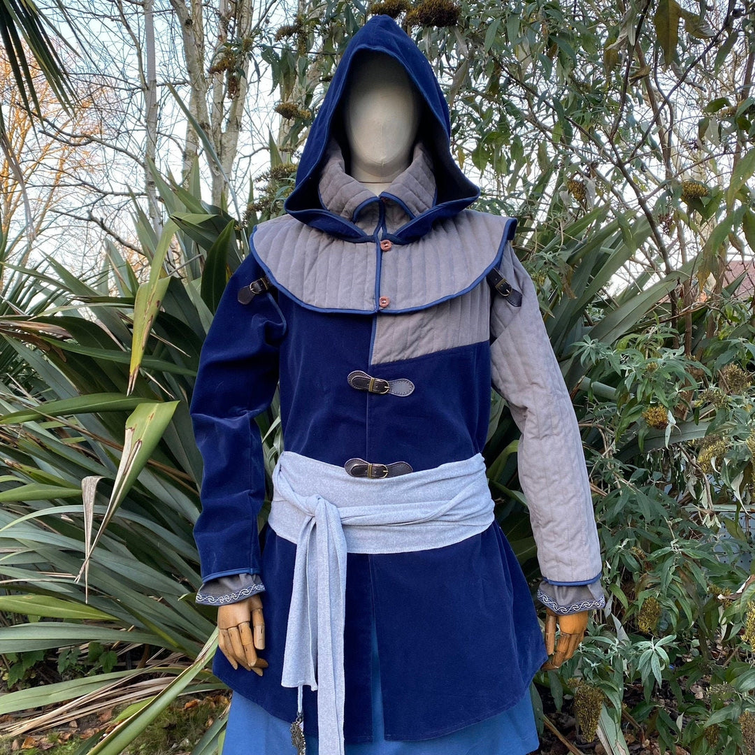 Azure medieval LARP costume with hood and belts in a wooded setting.
