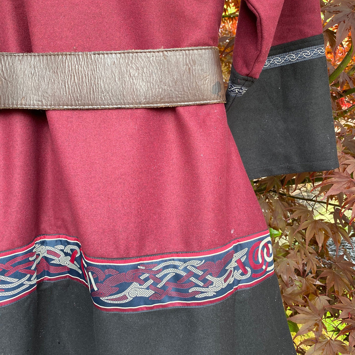 Side view of red black Viking tunic, detailed trim for LARP.