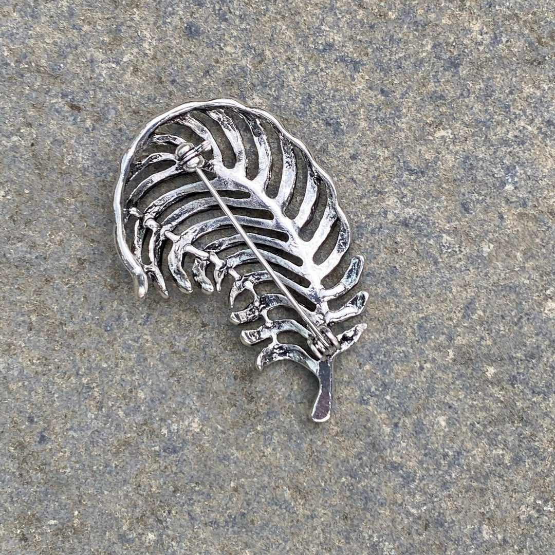 Dark silver fern-shaped brooch back view on stone for LARP.