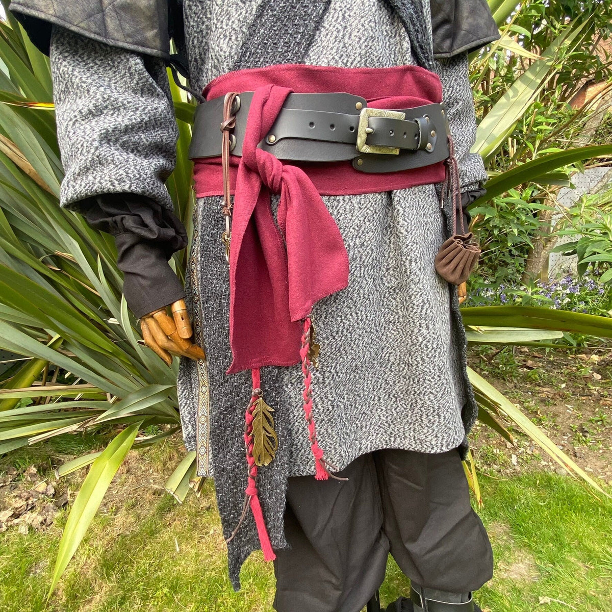 Black LARP belt on tunic with red sash and leather pouch, medieval style.