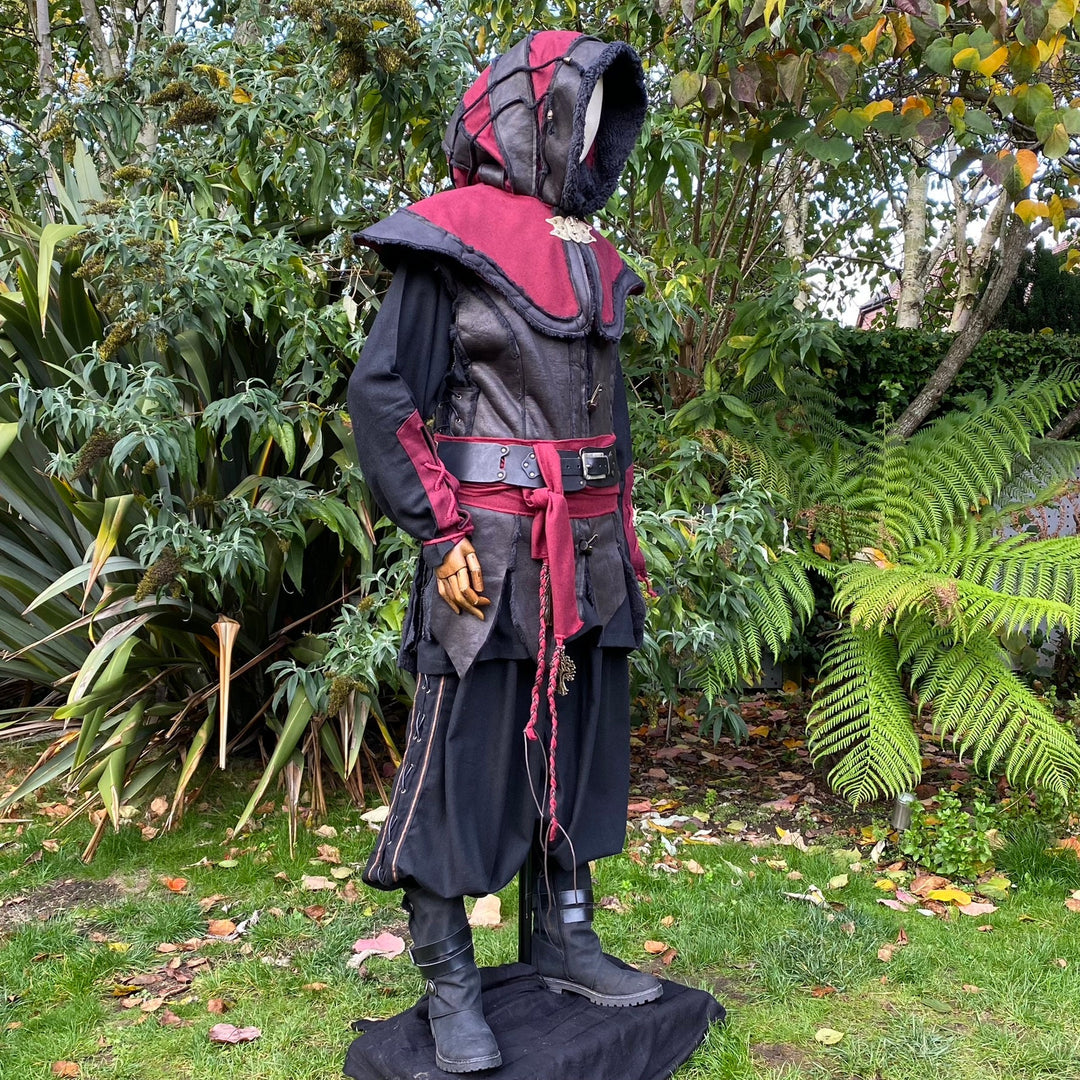 Medieval LARP outfit side view, featuring a red and black hood, waistcoat, shirt, and sash.
