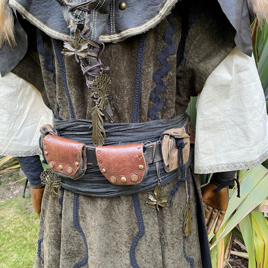 LARP feather charms with brass finish on medieval-style belt and cloak.