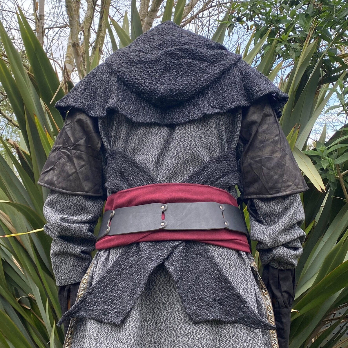 Back view of LARP belt on grey cloak; forest backdrop, medieval style.