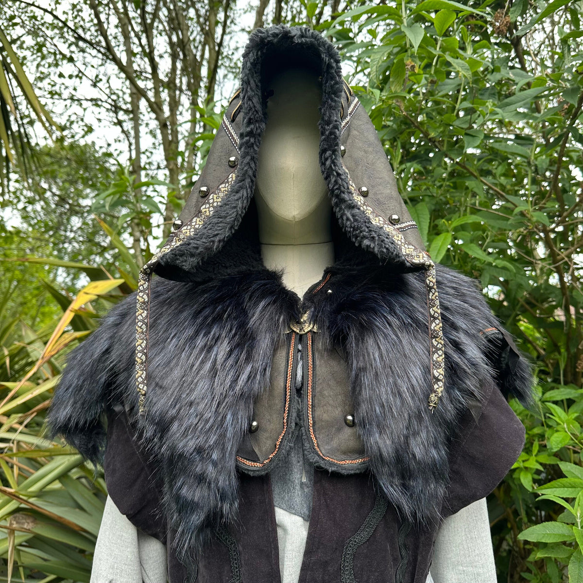 Medieval LARP hood in black faux leather with fur trim, nature backdrop.