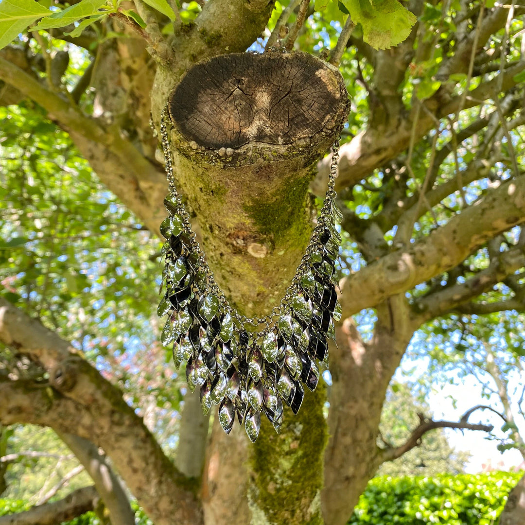 Medieval LARP leaf necklace hanging on tree branch, sunlight through foliage.