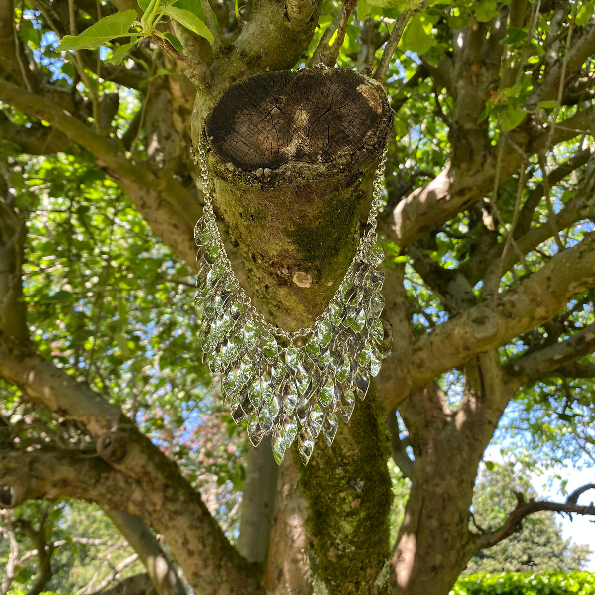 Silver chainmail necklace draped on a tree branch, LARP medieval style.
