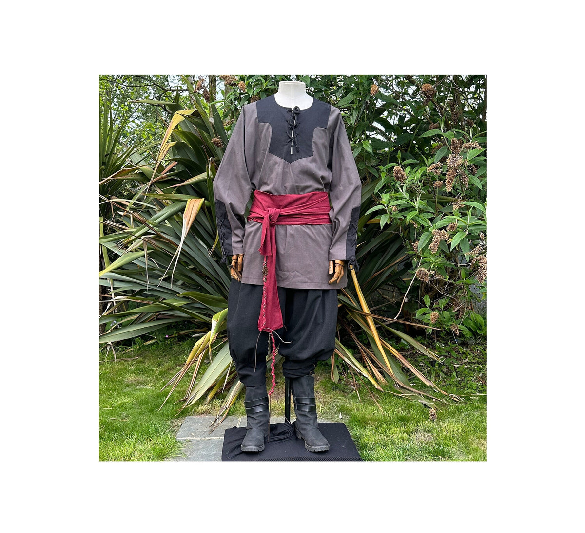 Medieval LARP outfit on mannequin, grey shirt, red sash.