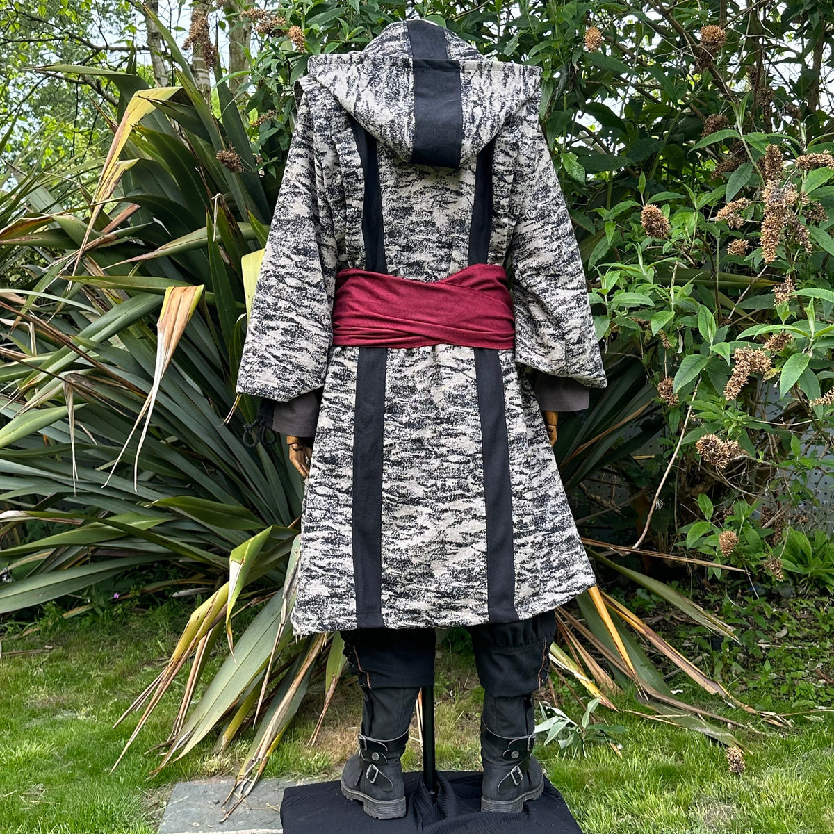 Medieval LARP costume back view, featuring brown and black hooded robe, two-tone shirt, trousers.