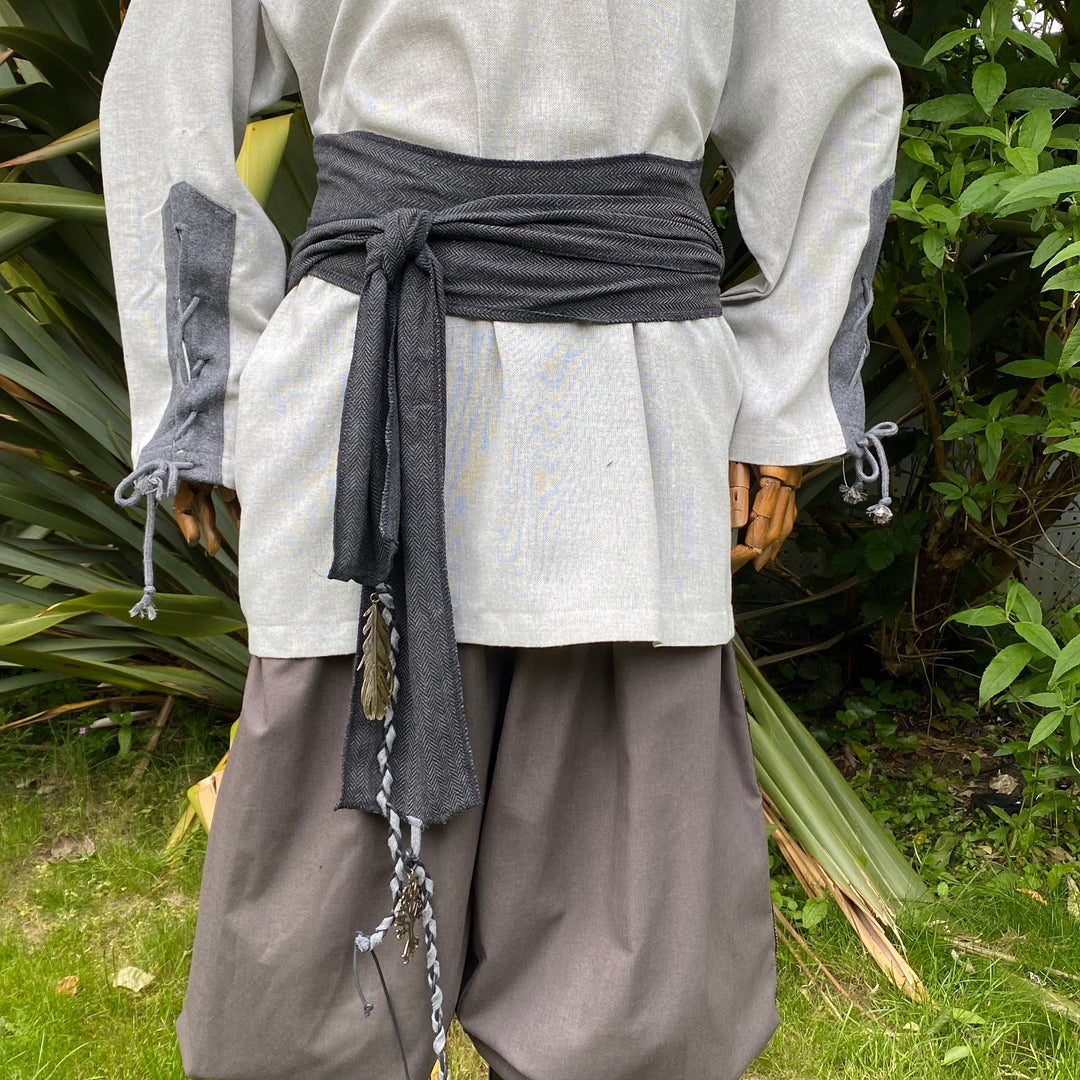 Dark grey LARP sash tied in knot with feather detail over tunic.