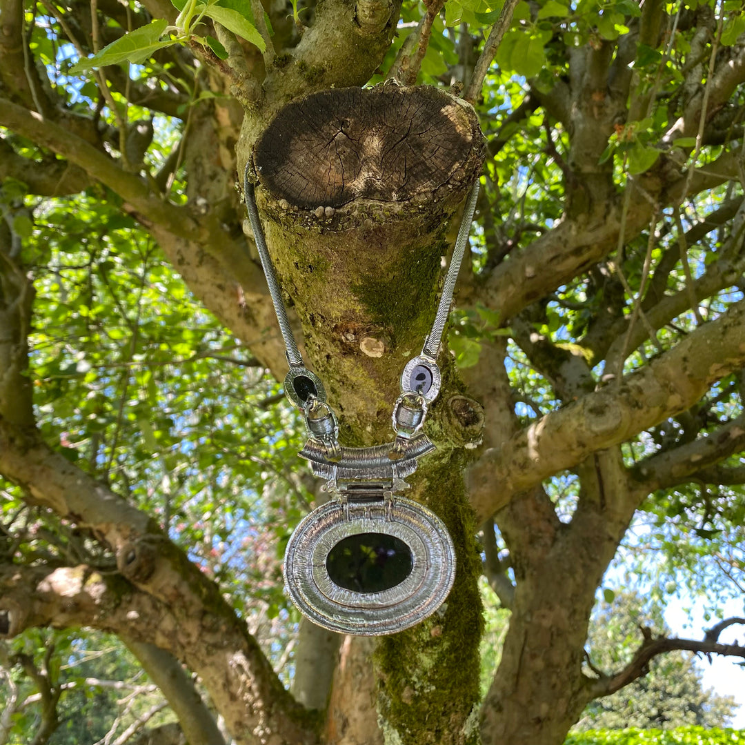 Silver Celtic necklace with black gem hanging on a tree branch for medieval LARP.