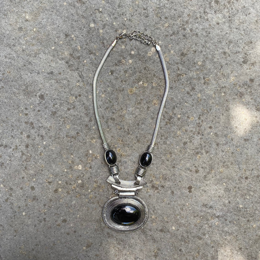 Celtic necklace with oval black gem, stone backdrop, for medieval LARP attire.
