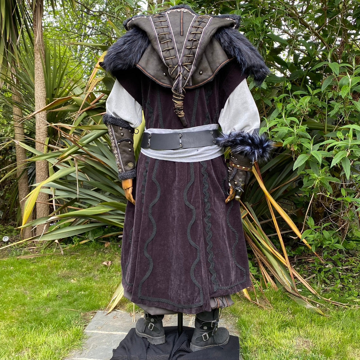 Back view of medieval LARP outfit with fur-trimmed hood and vambraces.