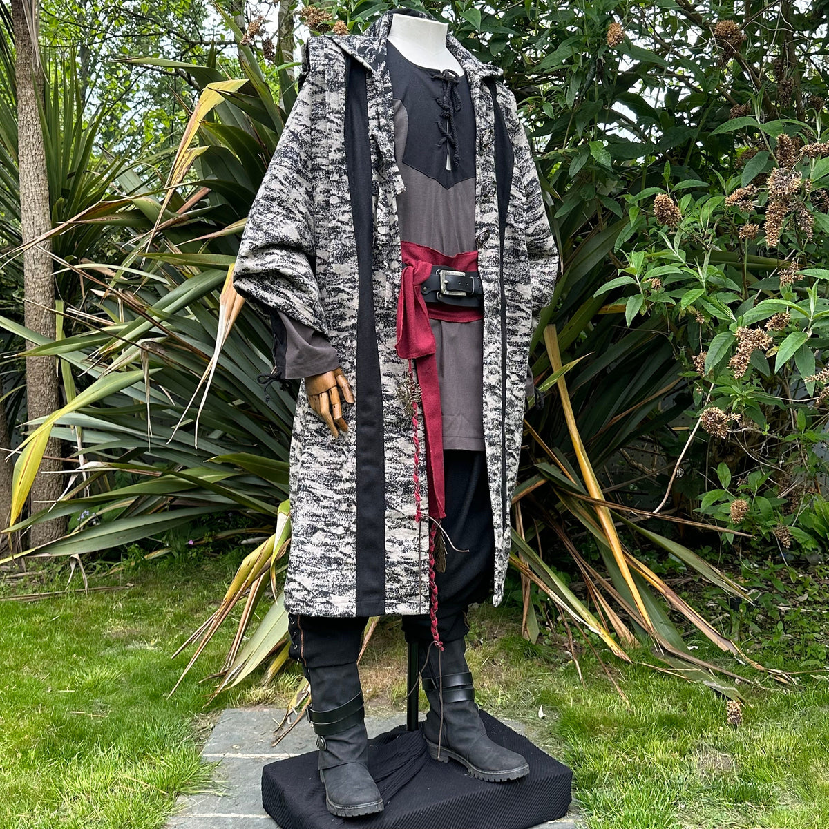 Medieval LARP costume side view, featuring brown and black hooded robe, two-tone shirt, trousers.