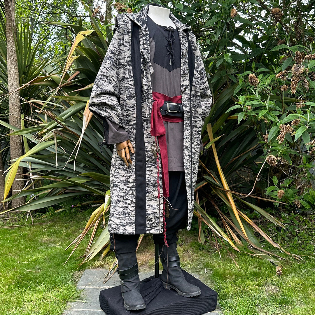 Medieval LARP costume side view, featuring brown and black hooded robe, two-tone shirt, trousers.