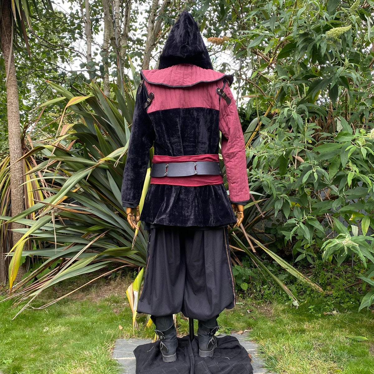 Back view of a medieval LARP costume, featuring a black and red gambeson jacket with removable.