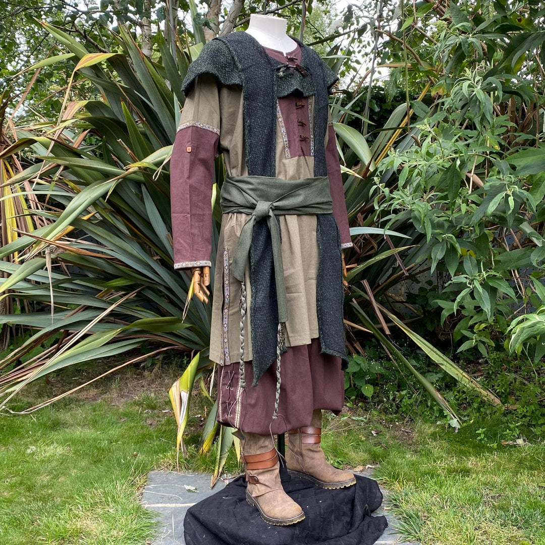 Mannequin in LARP tunic and hood, side garden view, earthy tones.