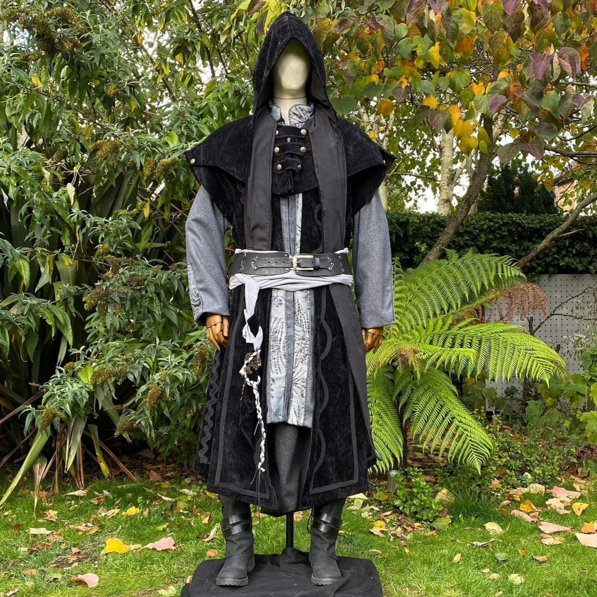 Mannequin in medieval LARP attire with hood and ornate belt.