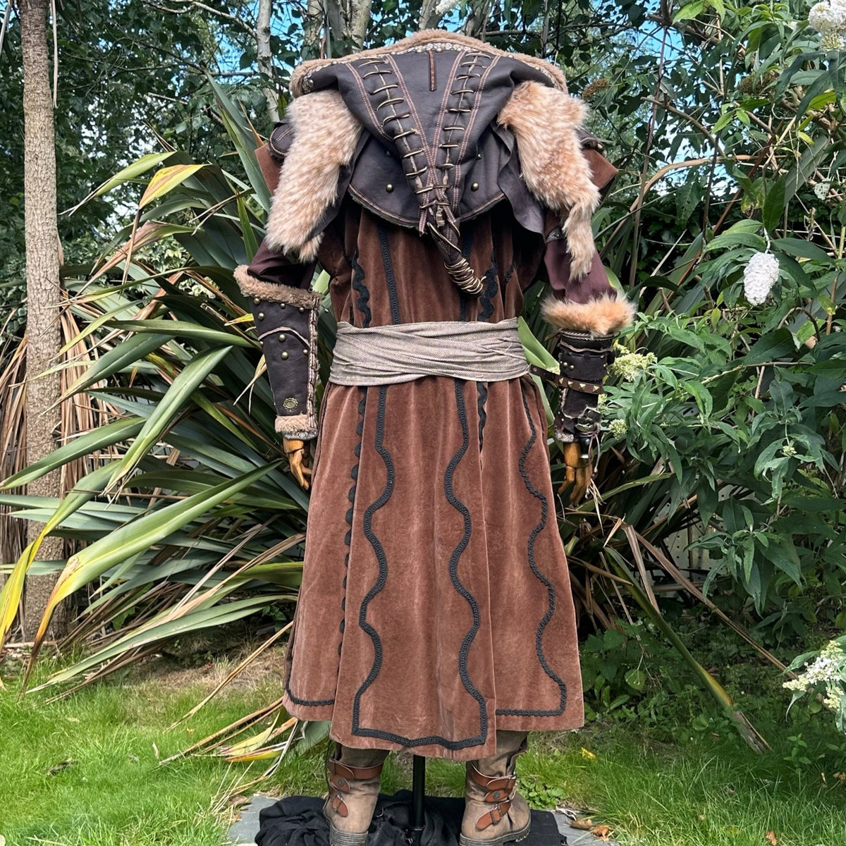 Medieval LARP outfit rear view, brown coat, fur trim, hood detail visible.
